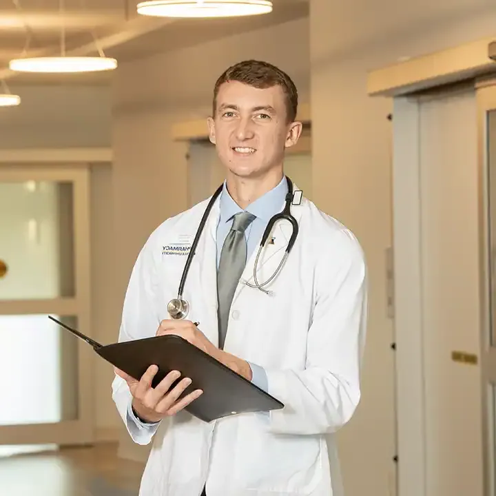 Male phamacy student wearing a stethoscope taking notes.