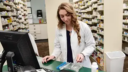 Pharmacist preparing a prescription at the counter in a pharmacy.