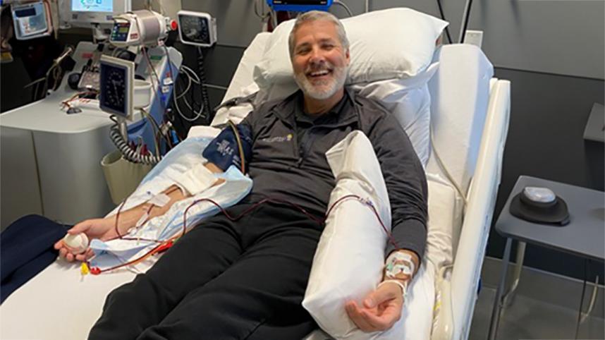 Dr. Will Smallwood smiling on hospital bed during his cancer treatment.